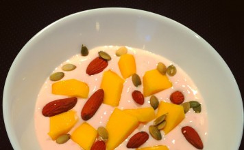 Yoghurt med proteinpulver, græskarkerner, sprøde mandler og sød mango