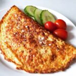 Osteomelet med løg og peberfrugt dertil tomater og agurk